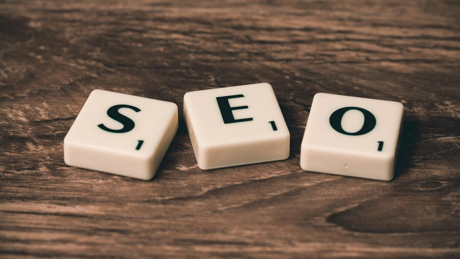 Scrabble tiles spelling 'SEO' on a wooden surface. Ideal for digital marketing themes.